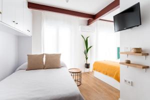 1 dormitorio con 1 cama y TV de pantalla plana en BeHouse Campana, en Sevilla