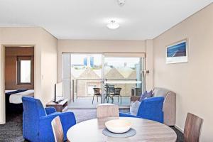 uma sala de estar com cadeiras azuis e uma mesa e uma vista em Hume Serviced Apartments em Adelaide