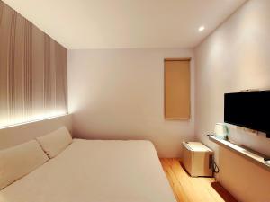 a small room with a bed and a flat screen tv at Partner Homestay in Hualien City