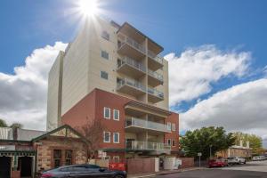 un edificio de apartamentos alto con el sol en el cielo en Hume Serviced Apartments, en Adelaida