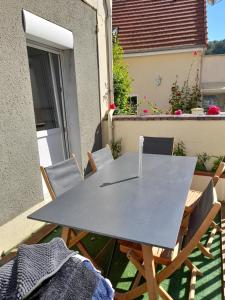 une table grise et des chaises sur un balcon dans l'établissement le neptune, à Arromanches-les-Bains