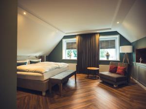 a bedroom with a bed and a chair and windows at Schlichte Hof GmbH in Bielefeld