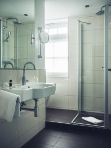 ein Bad mit einem Waschbecken und einer Dusche in der Unterkunft Schlichte Hof GmbH in Bielefeld