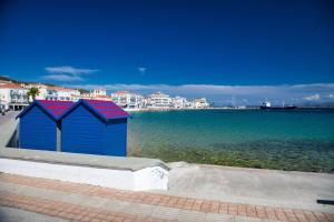 a blue shack with red roofs sitting next to the water at Argonaftis Spetses in Spetses