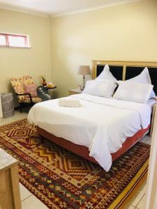 a bedroom with a large bed and a chair at Lovely self catering first floor apartment in Roodepoort