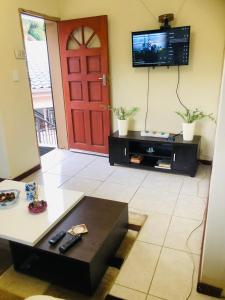 a living room with a red door and a tv at Lovely self catering first floor apartment in Roodepoort