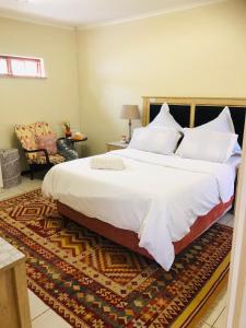 1 dormitorio con 1 cama grande con sábanas y almohadas blancas en Lovely self catering first floor apartment en Roodepoort