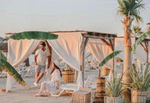 a man and woman walking on the beach with a tent at Hotel Akbulut & Spa in Guzelcamlı