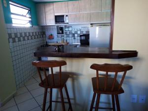 cocina con 2 taburetes y nevera en Condomínio Euro, en Natal