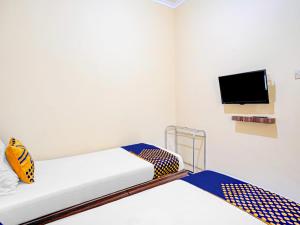 a room with two beds and a tv on the wall at SUPER OYO 90622 Hotel Galaksi in Ponorogo