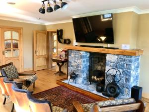 a living room with a fireplace with a tv above it at Ballyhourode House in Dún ar Aill
