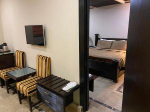 1 dormitorio con cama, espejo y silla en City Centre Suites, en Multán