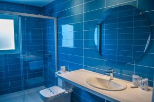 Baño de azulejos azules con lavabo y espejo en HOSTAL XUROY, en Sant Lluis
