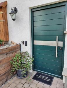 a green garage door on a house with a potted plant at Schöne EinZimmer Wohnung Zwischen Bodensee und Allgäu in Neukirch