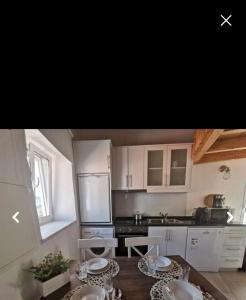 a kitchen with white cabinets and a table with plates on it at Casinhas Proença in Aljezur