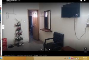 a living room with a chair and a christmas tree at Grace Hotel in Gobindpur +2 photos