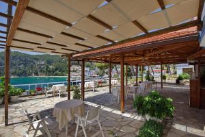 a patio with tables and chairs and a view of the water at Kavos Hotel in Patitiri