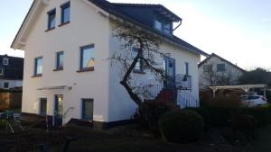 a white house with blue windows and a tree at Ferienwohnung Schneider in Marburg an der Lahn