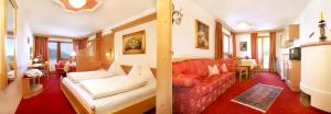 a living room with a red couch and a kitchen at Hotel Garni Concordia - Dolomites Home in Selva di Val Gardena