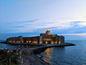 a castle in the middle of the ocean at night at Ostello Bella Calabria in Torre Ritani