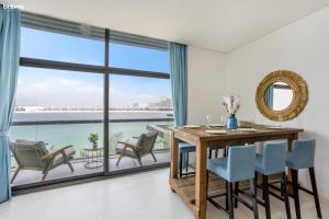 a dining room with a table and chairs and a large window at bnbmehomes - Rare Find on the Palm Jumeirah - 100 in Dubai