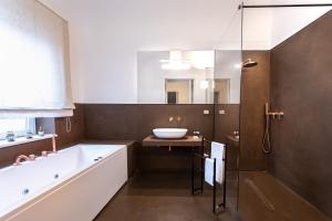 La salle de bains est pourvue d'une baignoire, d'un lavabo et d'une baignoire. dans l'établissement Riflessi Acireale Palace Suites, à Acireale