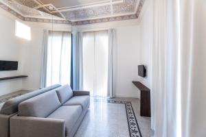 a living room with a couch and a tv at Riflessi Acireale Palace Suites in Acireale