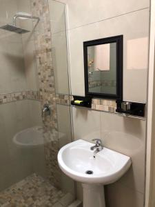 a bathroom with a sink and a shower with a mirror at Afsaal flats in Amanzimtoti