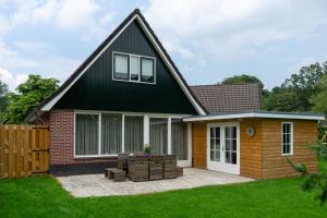 a house with a black roof and a patio at Kom in de Bedstee Magie! in Winterswijk