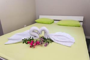 a bed with two towels and flowers on it at Anin Dvor Šekovići in Šekovići
