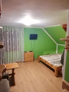 Pokoje Gościnne Alexandra في سترونيش لونسكي: غرفة نوم بجدران خضراء وسرير وطاولة