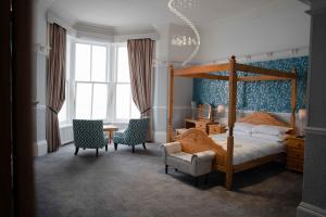 a bedroom with a canopy bed and two chairs at Delmont Hotel in Scarborough
