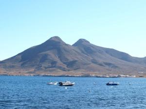 trois bateaux dans l'eau avec une montagne en arrière-plan dans l'établissement Isleta del Moro TERRAZA VISTAS MAR Exclusiva 60 m2 WIFI, à La Isleta del Moro