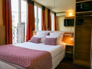a bedroom with a large bed with a window at Hôtel de France Quartier Latin in Paris