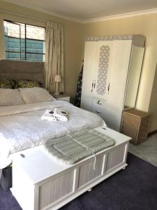 a bedroom with a white bed and a dresser at Cozy One bedroom garden cottage in Roodepoort