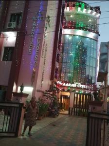 齋浦爾的住宿－Hotel Aarjee Crescent Jaipur，一位妇女,在一座带圣诞灯的建筑前行走