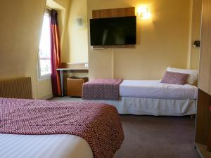 a hotel room with two beds and a flat screen tv at Hôtel de France Quartier Latin in Paris