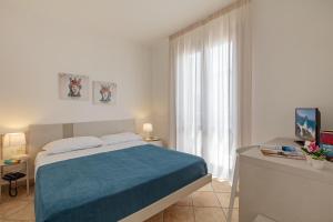 a white bedroom with a bed and a window at Hotel Sikania in San Vito lo Capo