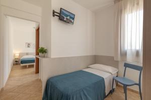 a bedroom with a bed and a blue chair at Hotel Sikania in San Vito lo Capo