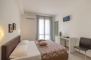a bedroom with a bed and a desk and a chair at Hotel Sikania in San Vito lo Capo