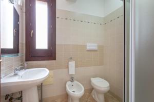 a bathroom with a sink and a toilet and a window at Hotel Sikania in San Vito lo Capo
