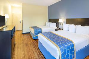 a hotel room with two beds and a flat screen tv at Days Inn by Wyndham Macon I-75 North in Macon