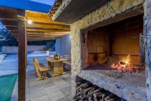 a stone fireplace in a patio with a table at Holiday Home Dijamant in Kučiće