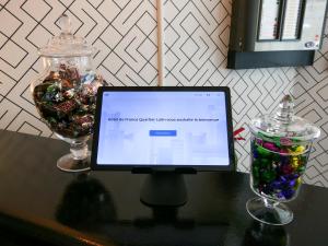 a computer monitor sitting on a table with two glasses at Hôtel de France Quartier Latin in Paris