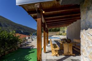 a patio with a table and chairs under a wooden roof at Holiday Home Dijamant in Kučiće