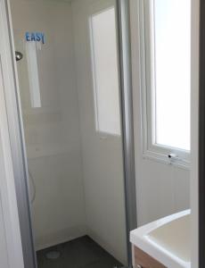 baño con ducha, lavabo y ventana en Assist' Mobil Home 377 - Mobil Home 3 chambres 6 Personnes en Onzain