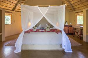 Umlani Bushcamp في محمية صيد تيمبافاتي: سرير مع مظلة في الغرفة