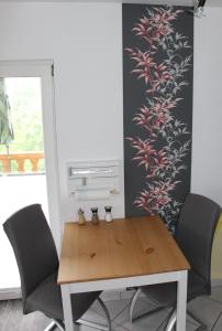 a dining room table with chairs and a wall with flowers at Ferienwohnung Löffler Nassau-Erzgebirge in Frauenstein