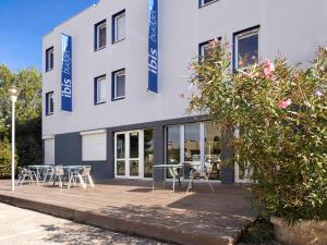 un bâtiment avec des tables et des chaises devant lui dans l'établissement ibis budget Arles Sud Fourchon, à Arles