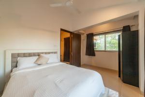 - une chambre avec un grand lit blanc et une fenêtre dans l'établissement Goa Junction by Daystar Ventures, à Anjuna